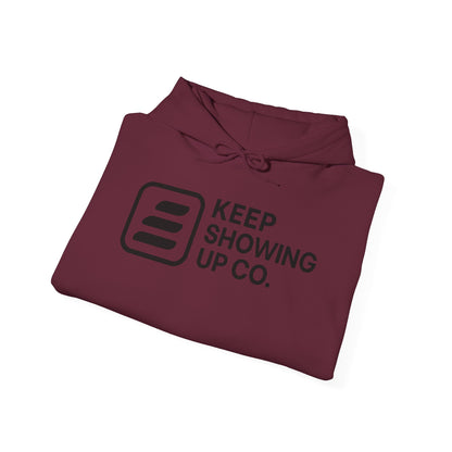 Folded maroon hoodie with 'KEEP SHOWING UP CO.' text on a white background